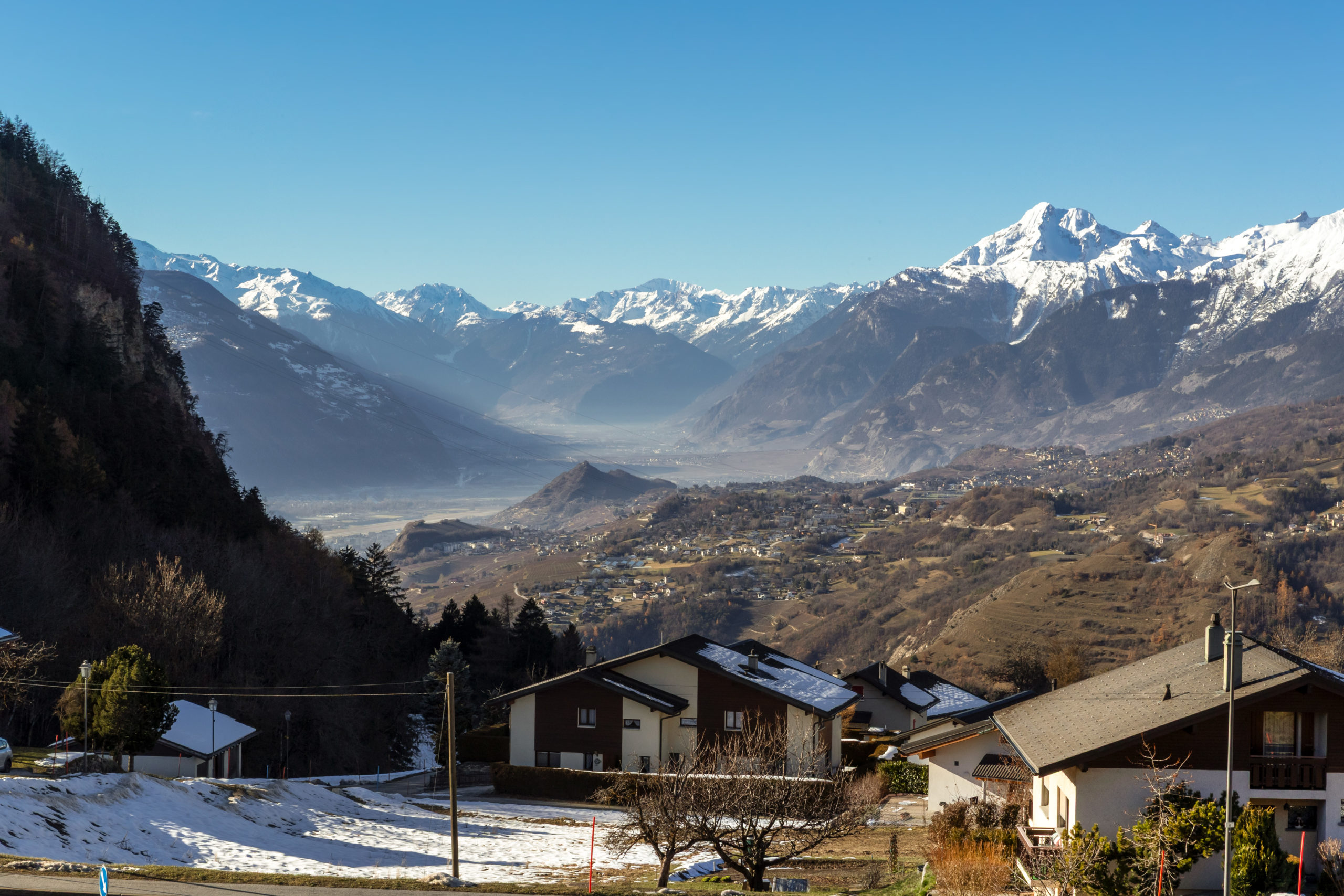 Alpenpanorama über ein Tal mit Wohnhäusern