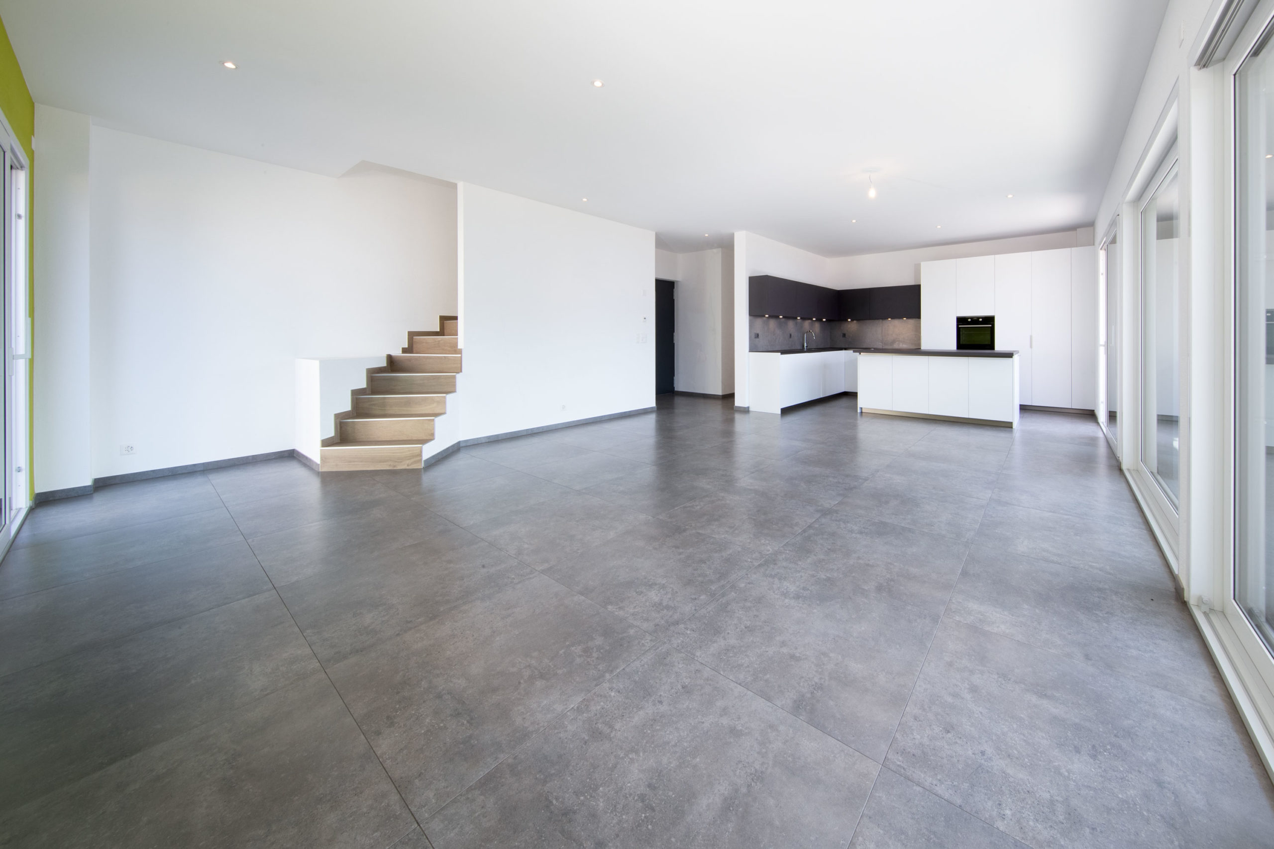 Großer, leerer Wohnbereich mit offener Küche und Treppe