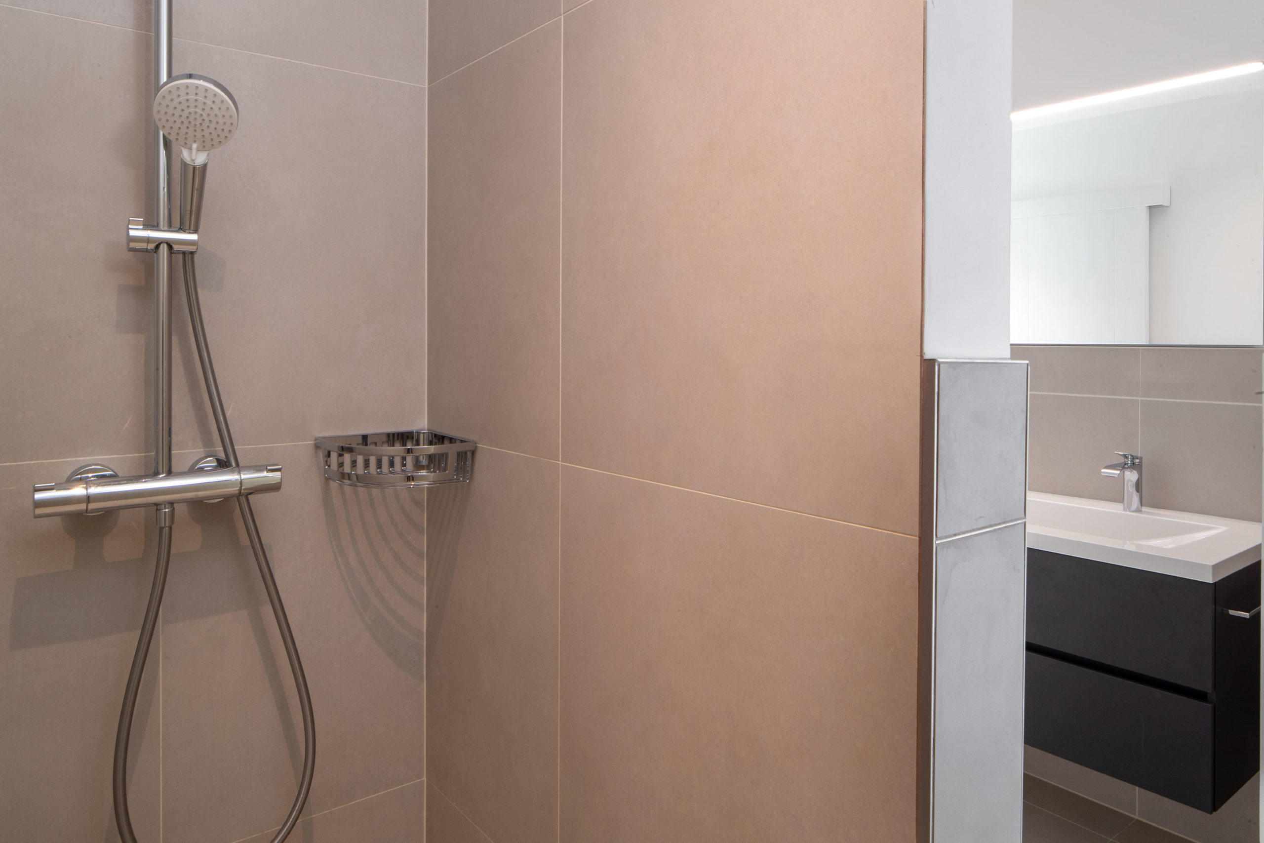 Moderne Dusche mit Waschtisch im Hintergrund