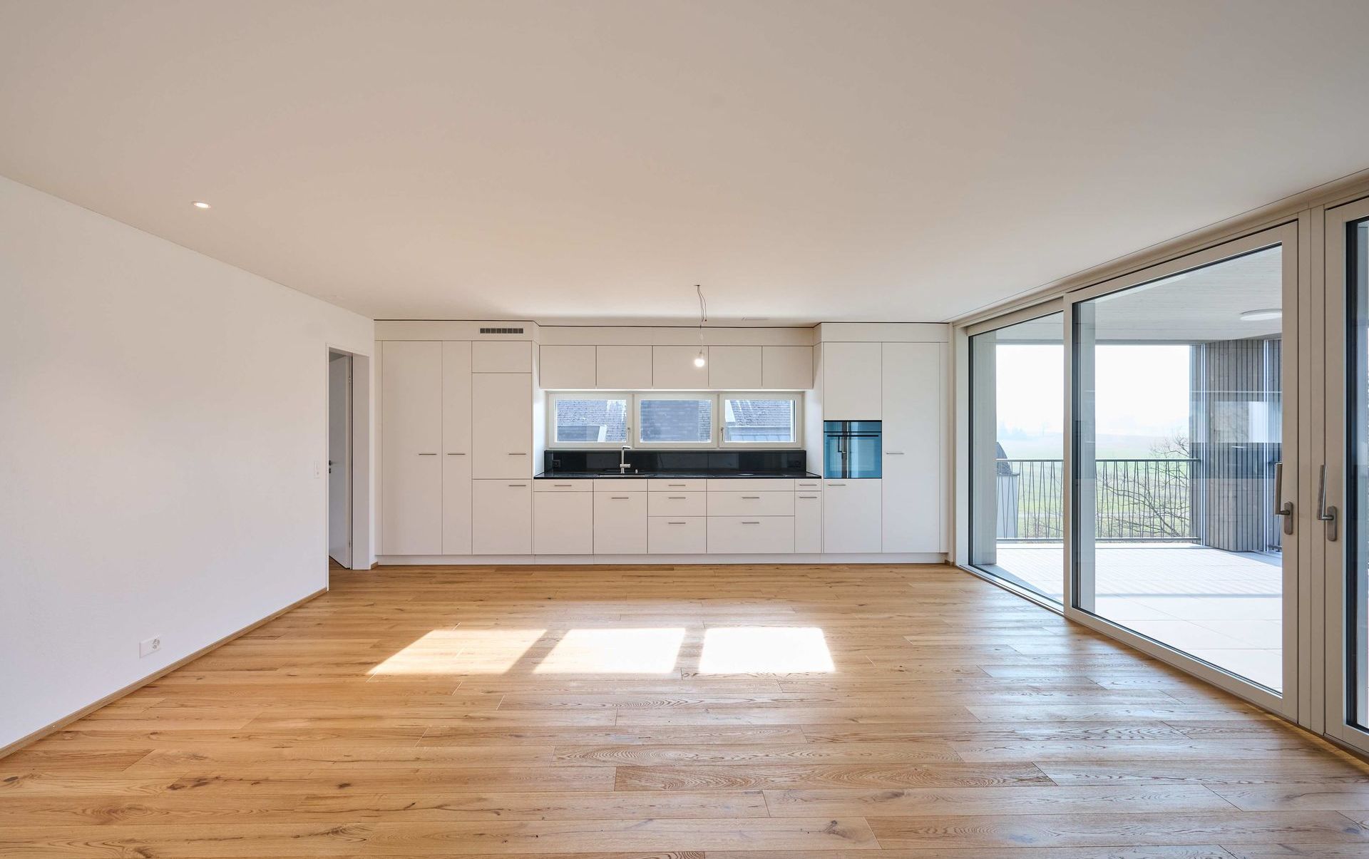Offener Wohnbereich mit integrierter Küche und großer Fensterfront
