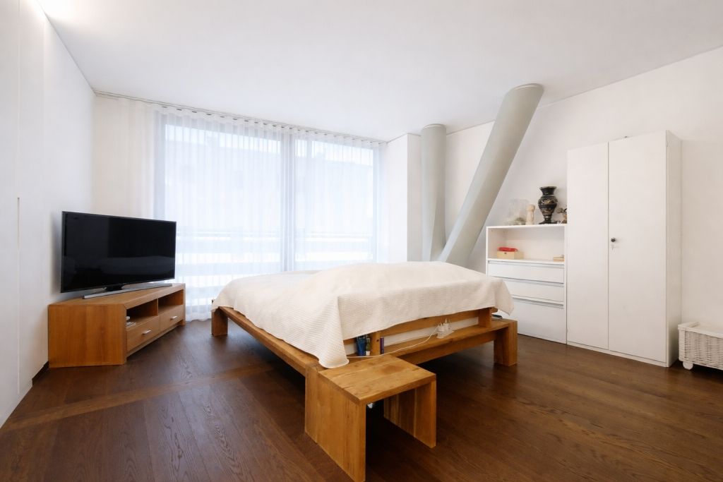 Helles Schlafzimmer mit Holzbett und TV