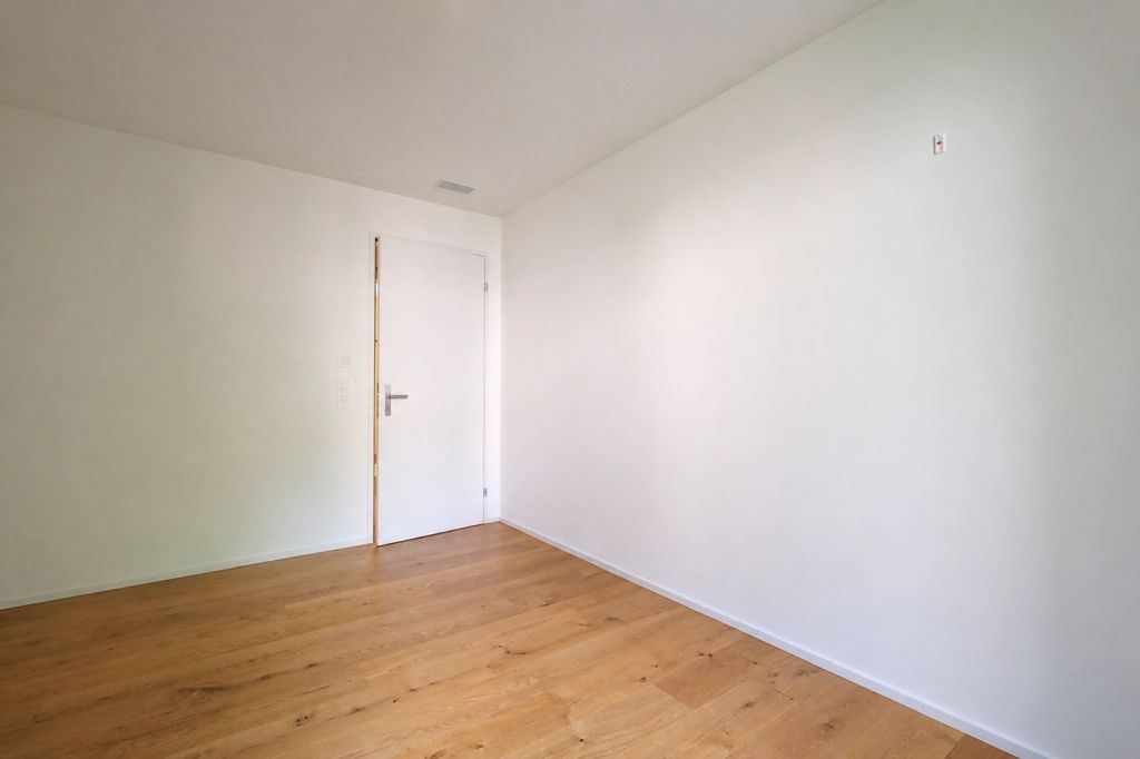 Leerer, heller Raum mit Holzboden und weißer Tür