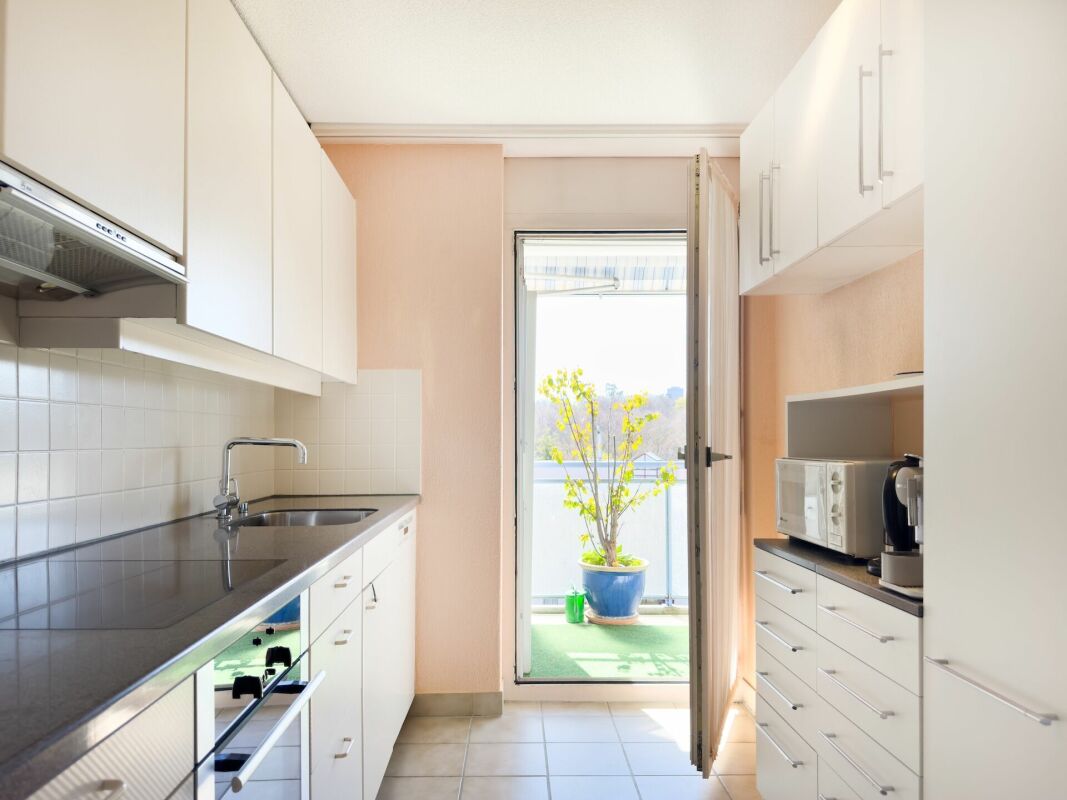 Schmale helle Küche mit Zugang zum Balkon