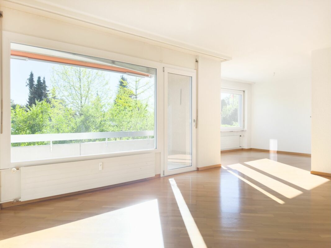 Helles, leeres Wohnzimmer mit Balkon und großem Fenster