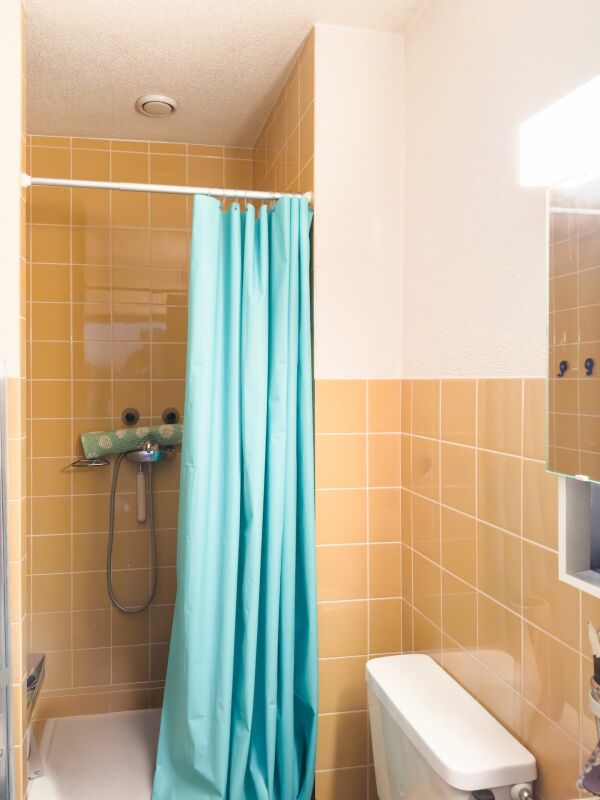 Badezimmer mit Duschbereich und türkisfarbenem Vorhang