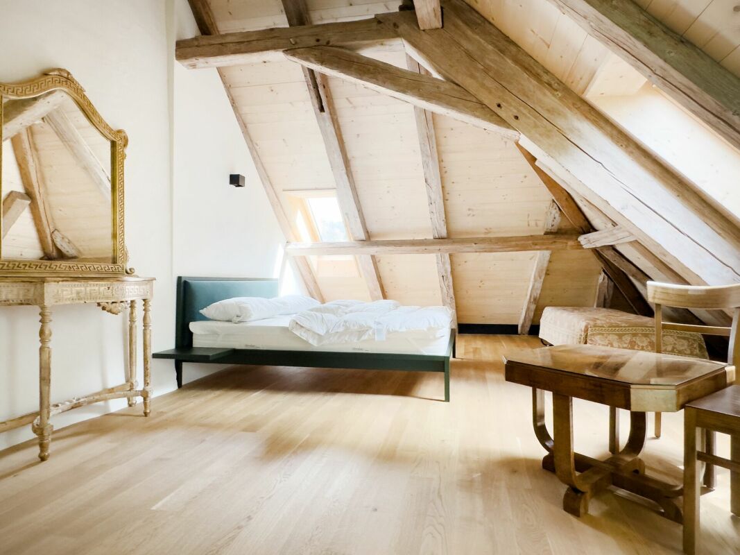 Dachzimmer mit Holzbalken und Einzelbett