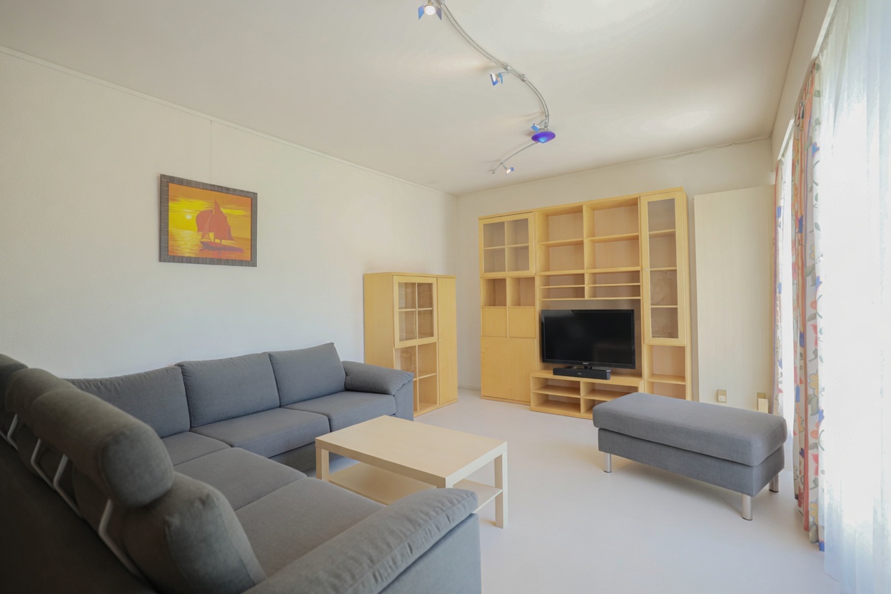 Helles Wohnzimmer mit grauer Eckcouch und Medienwand