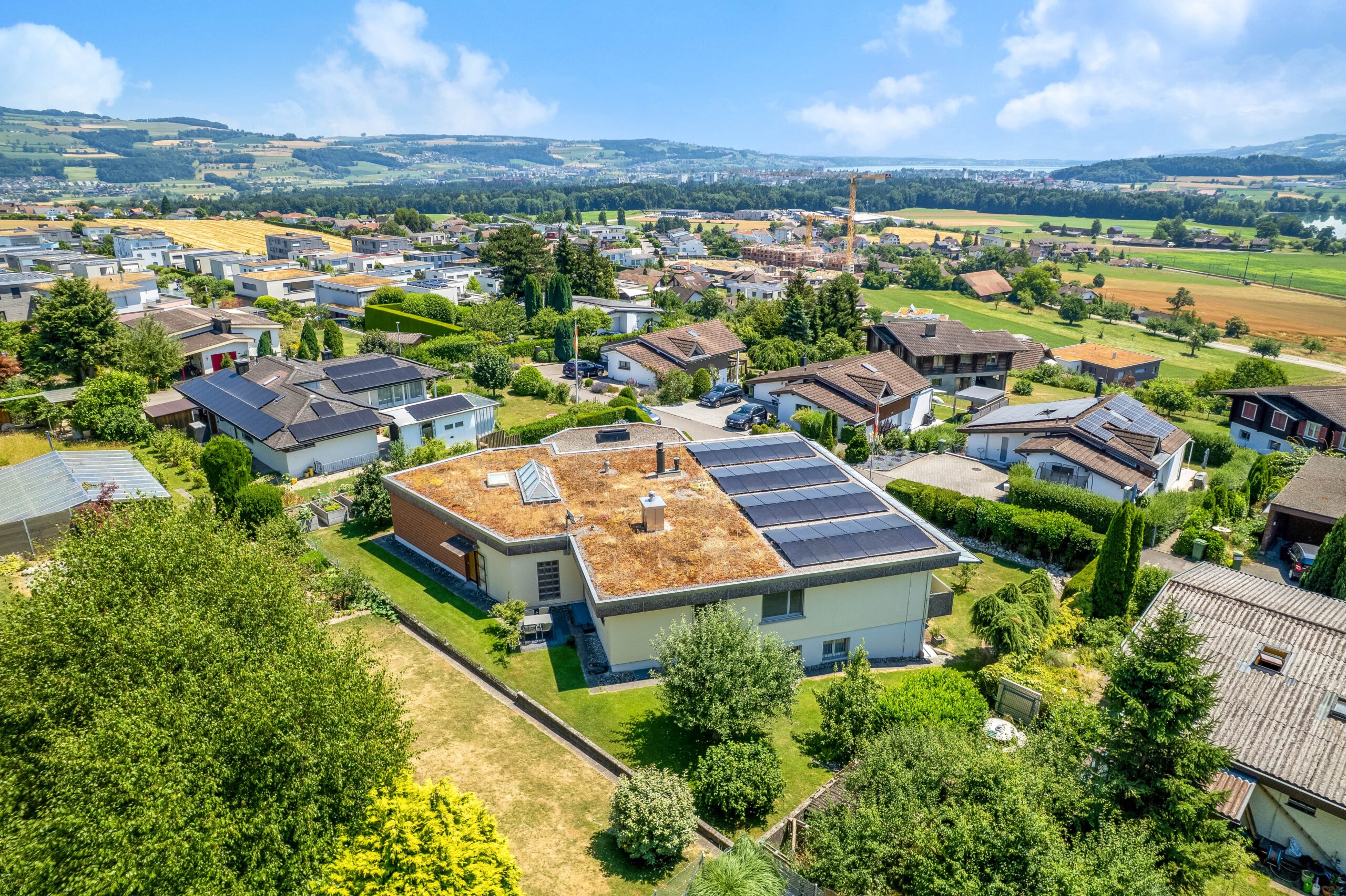 Luftaufnahme eines Wohngebiets mit Photovoltaik und Fernblick