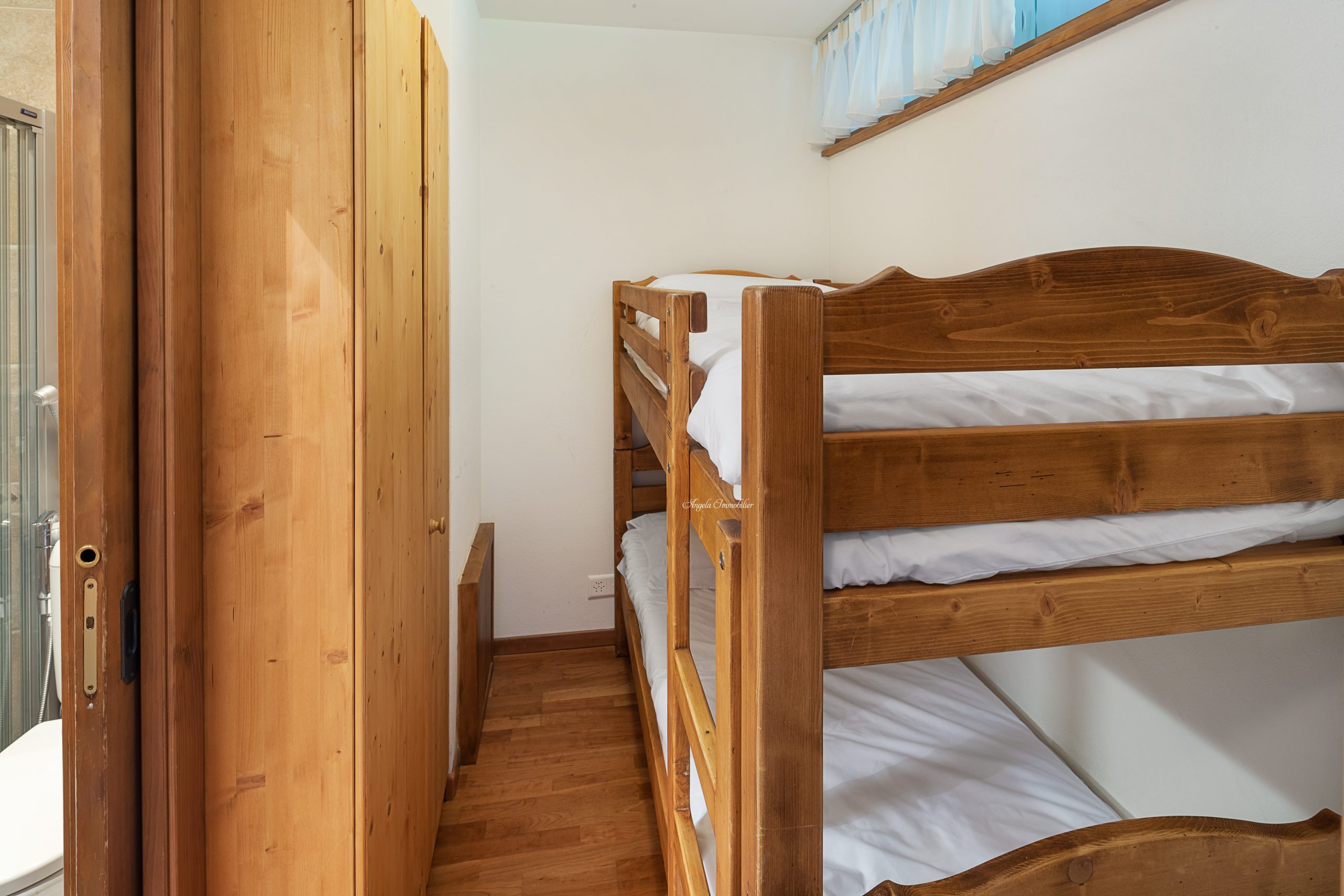 Kleines Schlafzimmer mit Etagenbett und Holzschrank