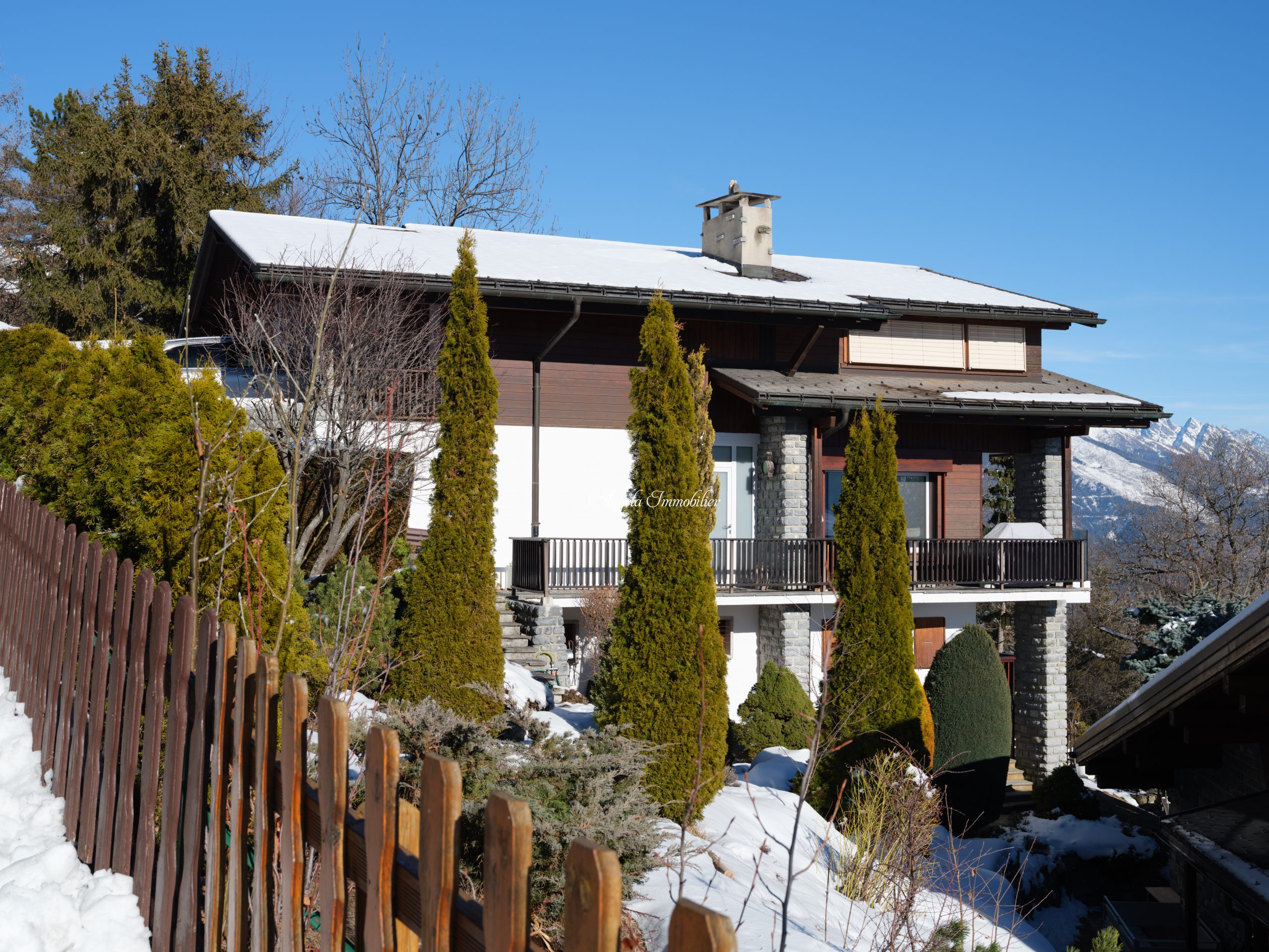 Schneebedecktes Alpenhaus mit Garten