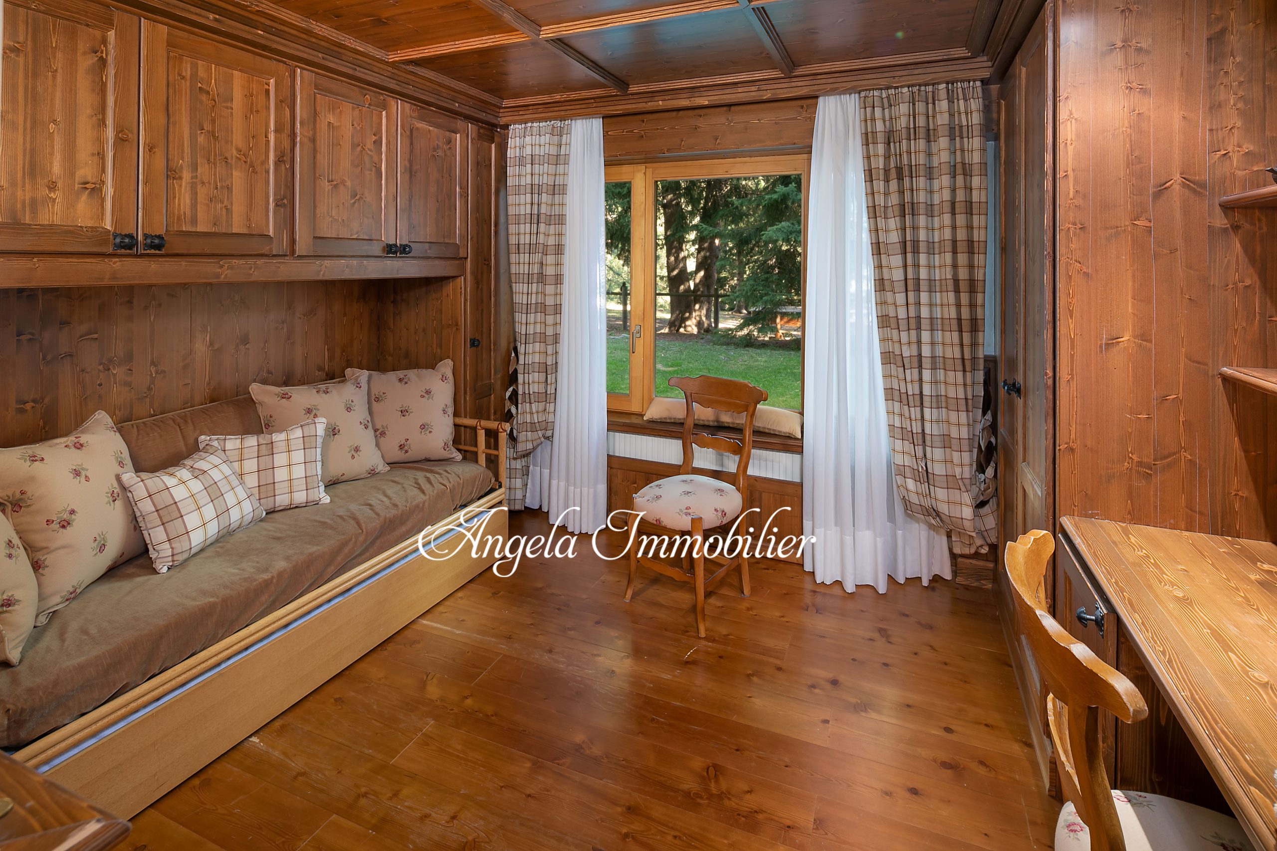 Gemütliches holzgetäfeltes Zimmer mit Sitzbank und Fensterblick