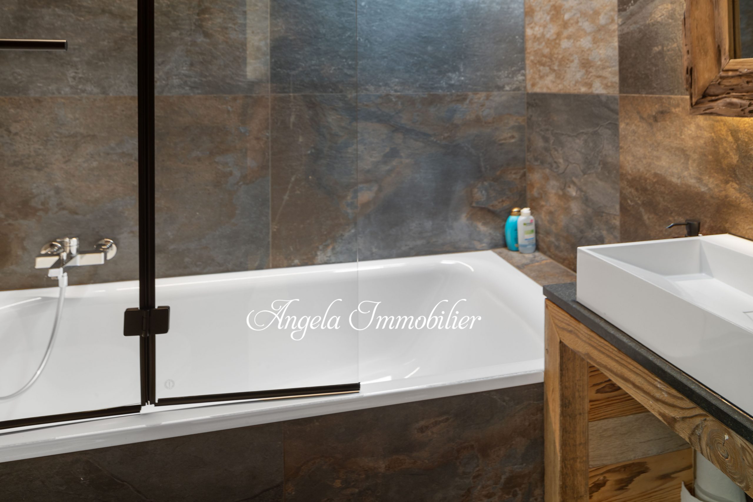 Luxuriöses Badezimmer mit Badewanne und Natursteinwand