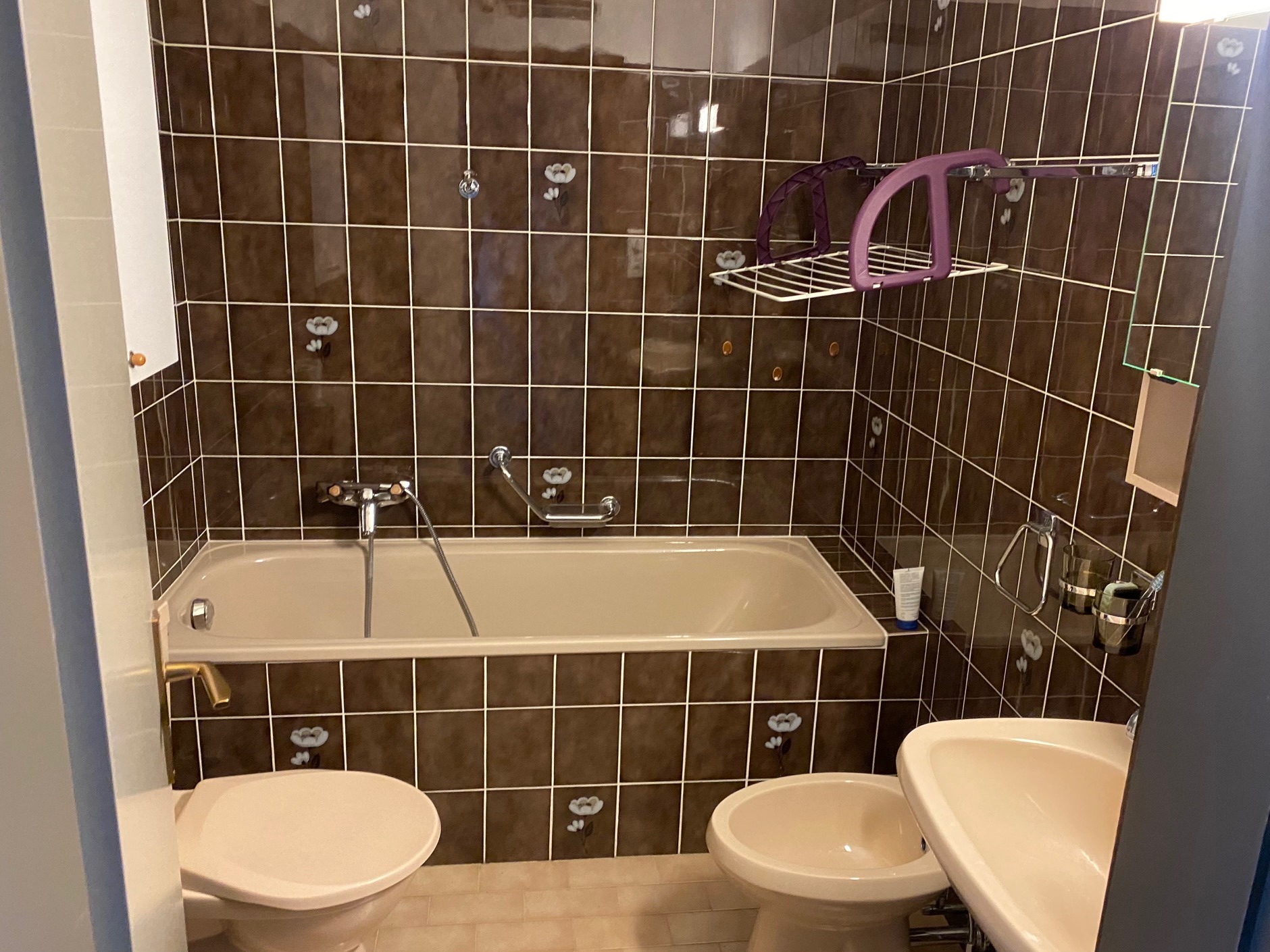 Badezimmer mit Badewanne und braunen Wandfliesen
