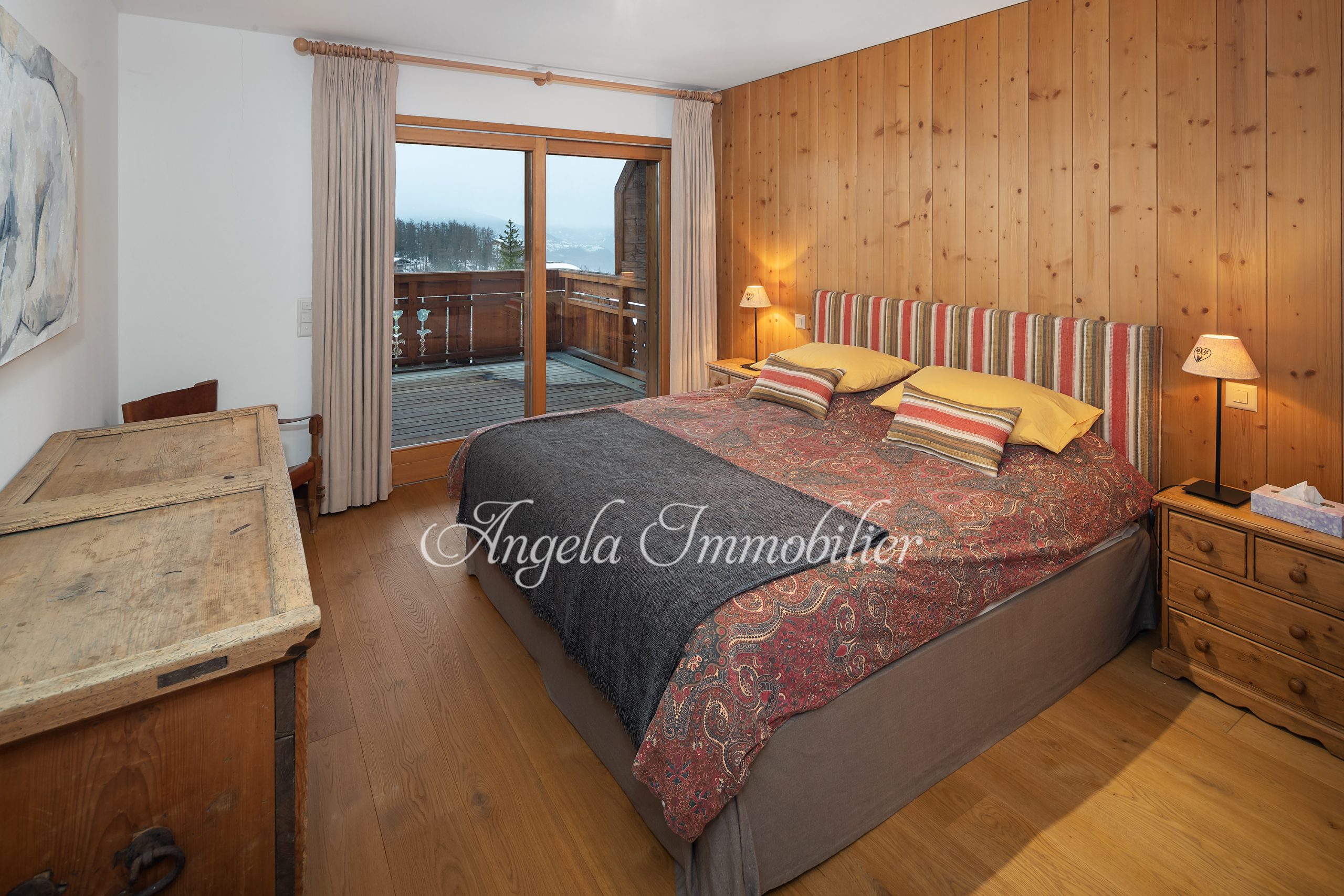 Gemütliches Schlafzimmer mit Holzverkleidung und Balkonblick