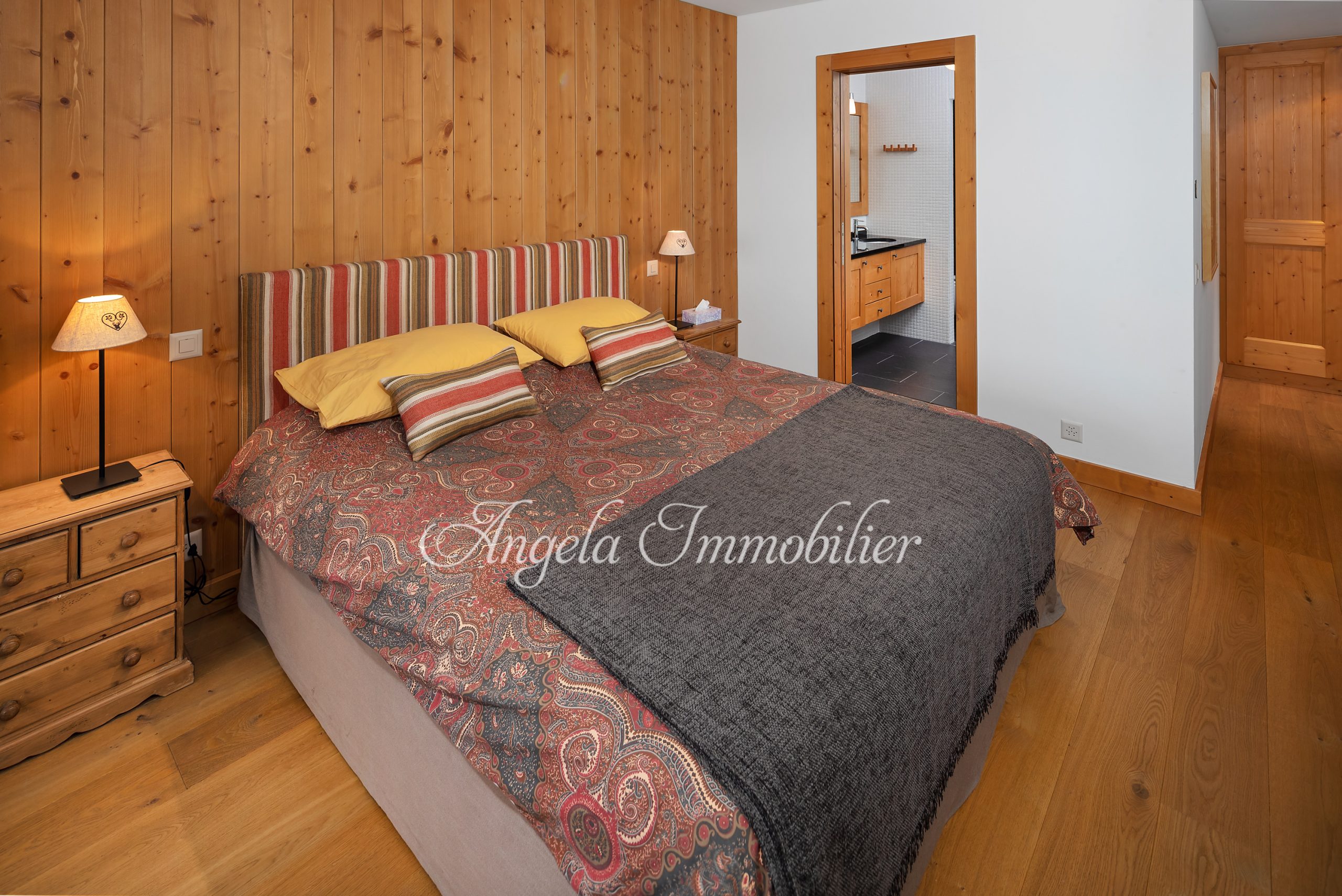 Gemütliches Schlafzimmer mit Holzwand und Badzugang
