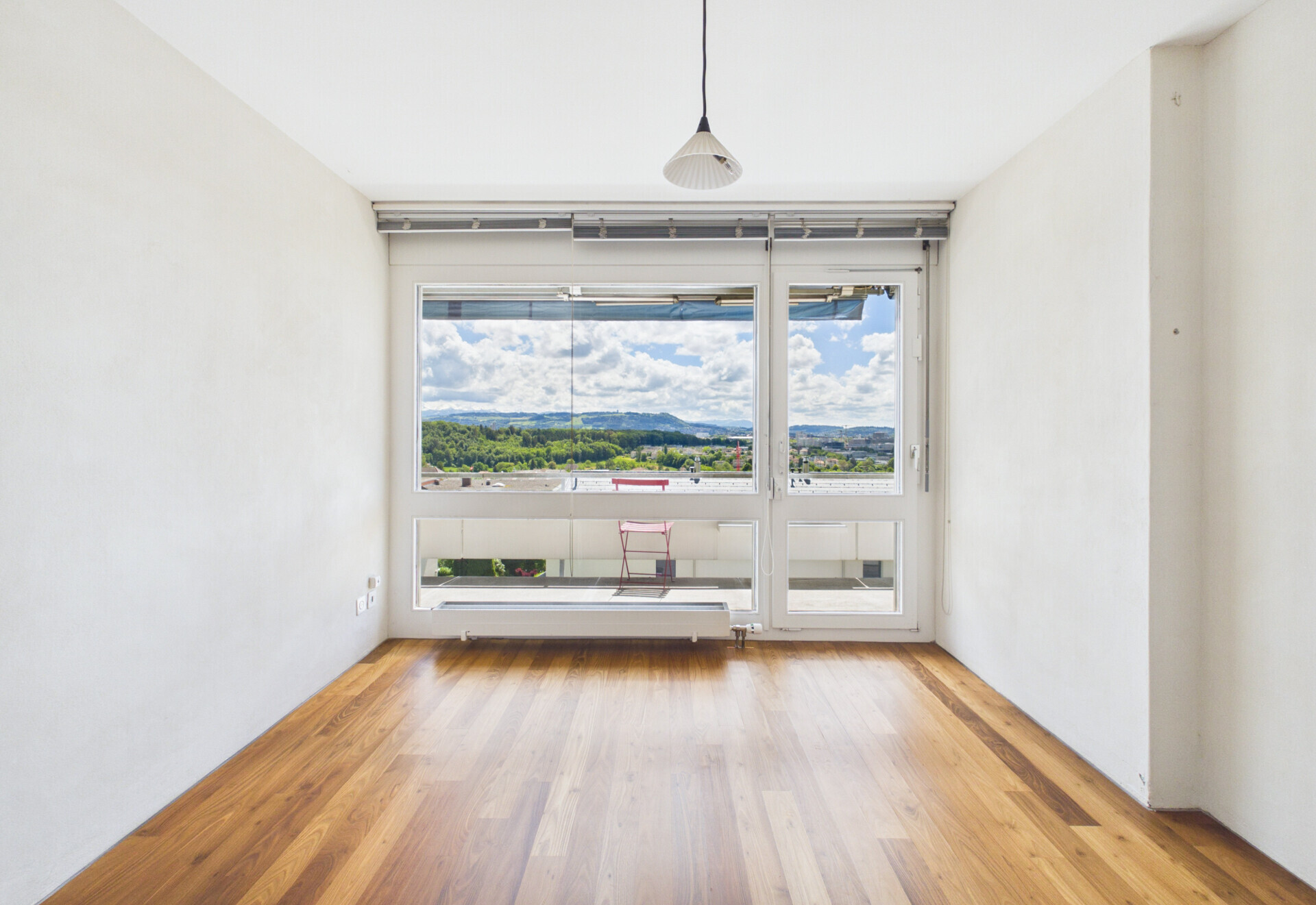 Heller Raum mit großer Fensterfront und Parkettboden