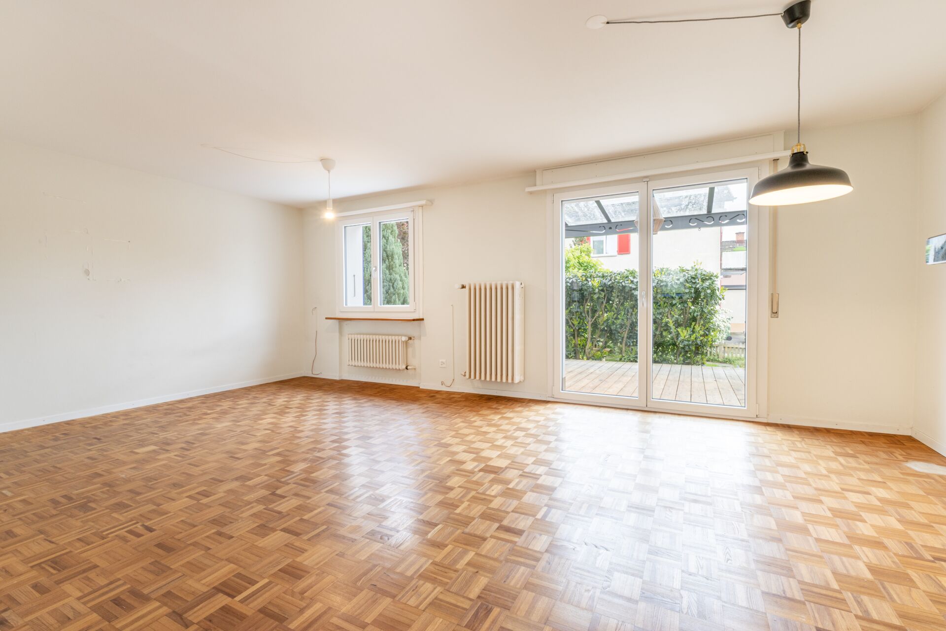 Heller leerer Wohnraum mit Parkett und Terrassenzugang