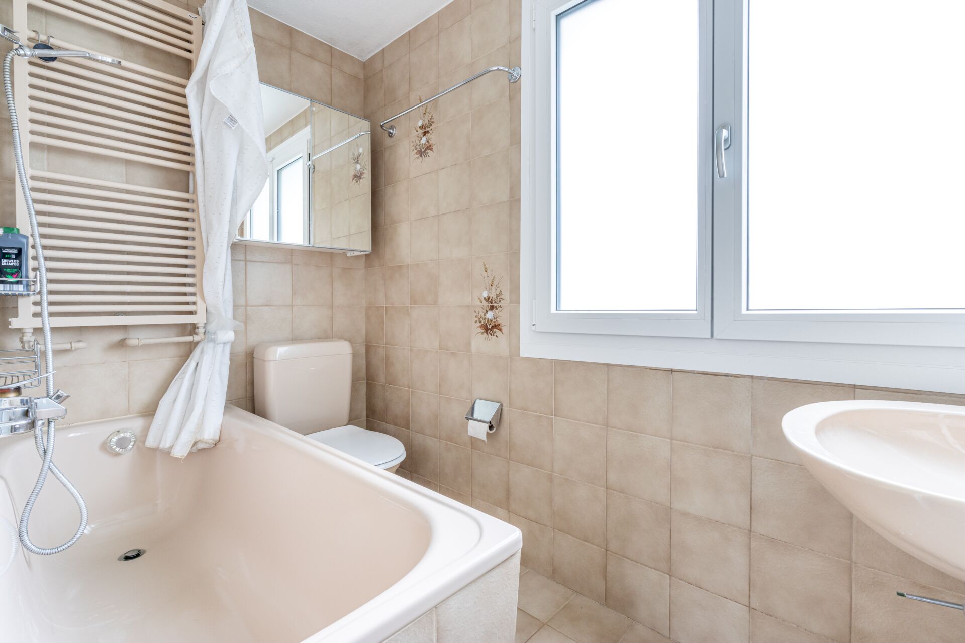 Helles Badezimmer mit Badewanne, Fenster und WC