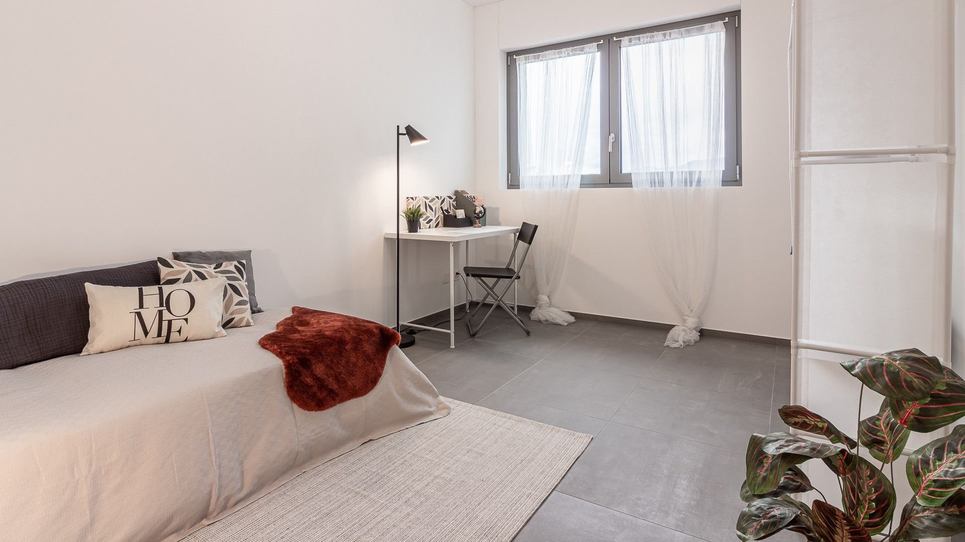 Helles, schlicht eingerichtetes Schlafzimmer mit Arbeitsbereich
