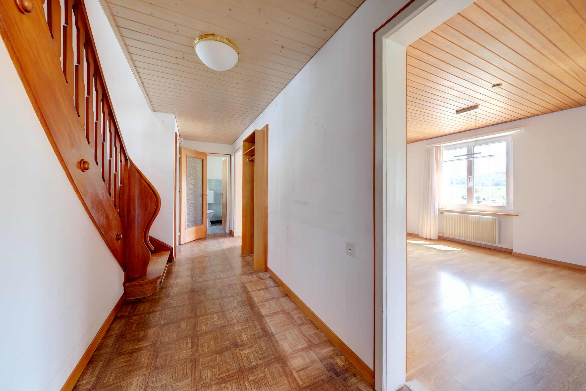 Heller Flur mit Treppe und angrenzendem Raum