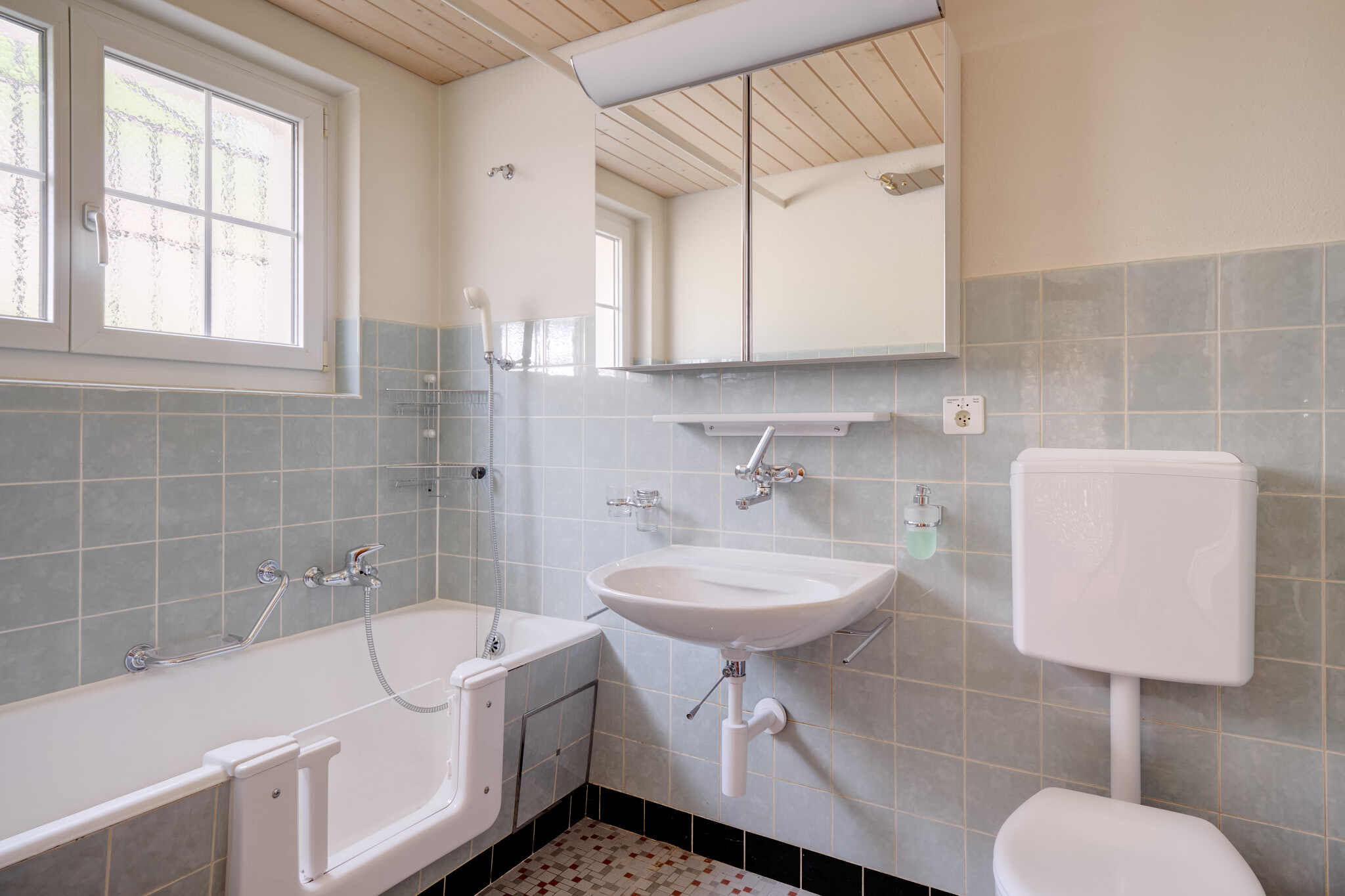 Helles Badezimmer mit Badewanne, Waschbecken und Spiegelschrank