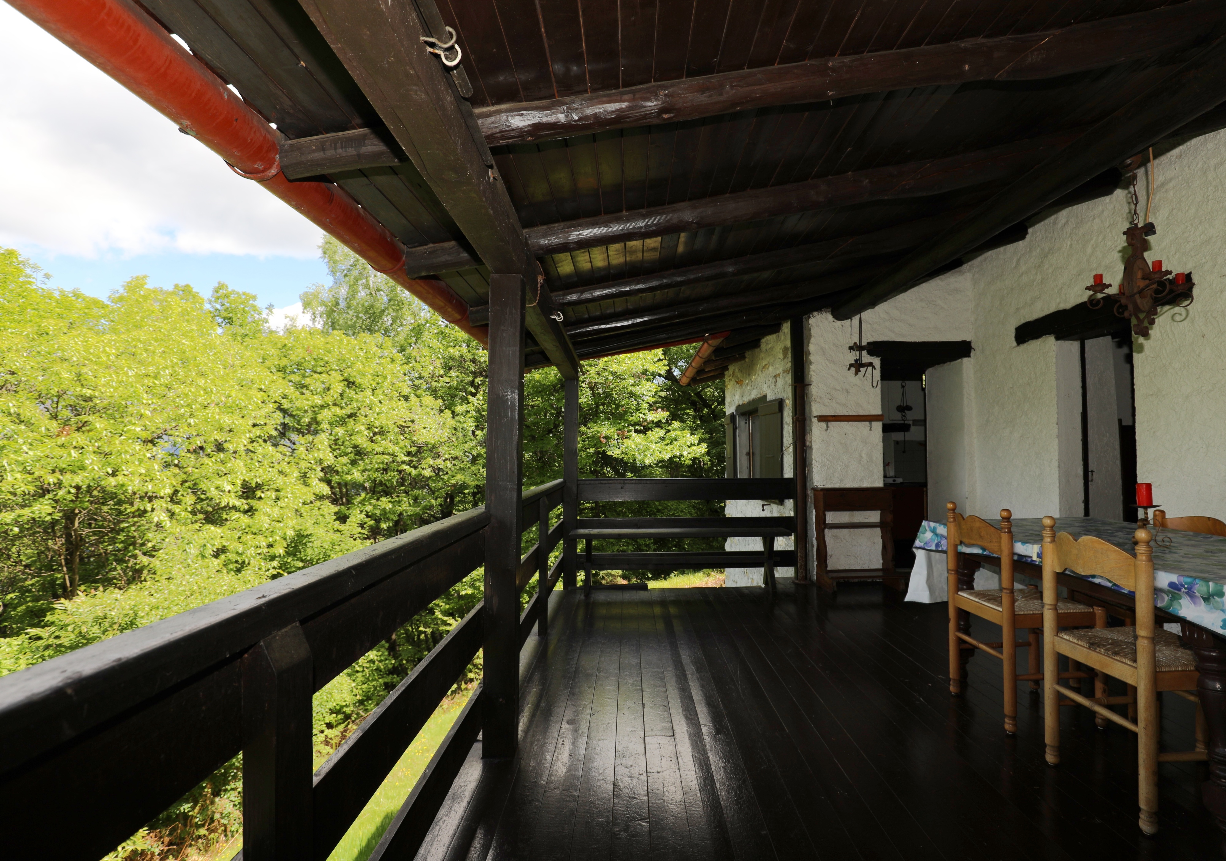 Überdachte Holzveranda mit Gartenblick