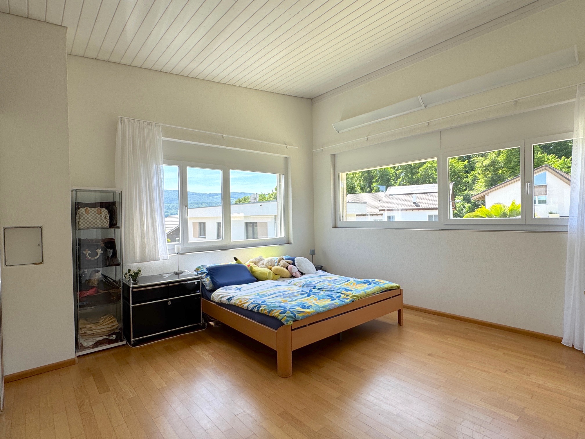 Helles Schlafzimmer mit großen Fenstern und Holzfußboden