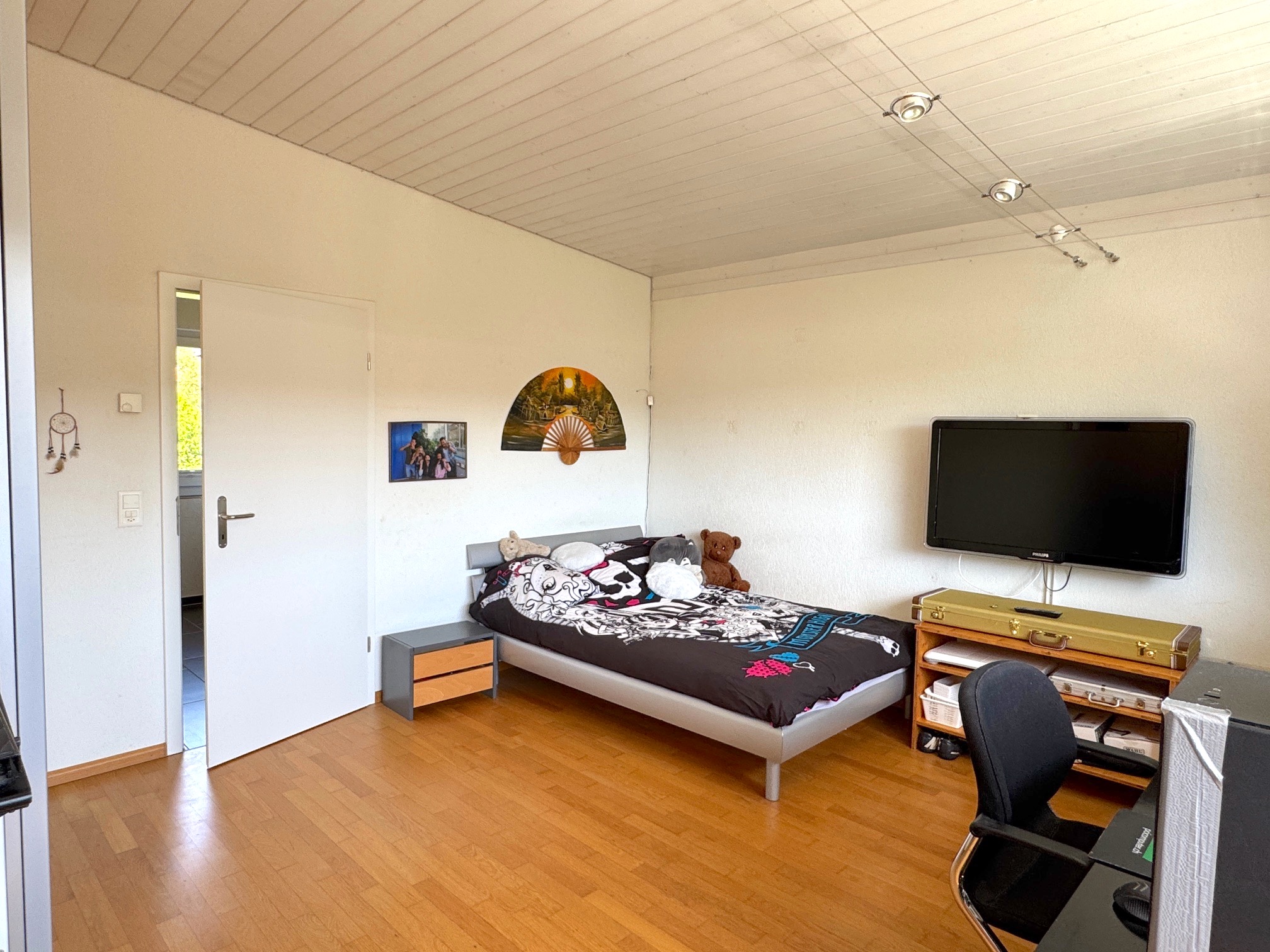 Helles Schlafzimmer mit Bett und Fernseher