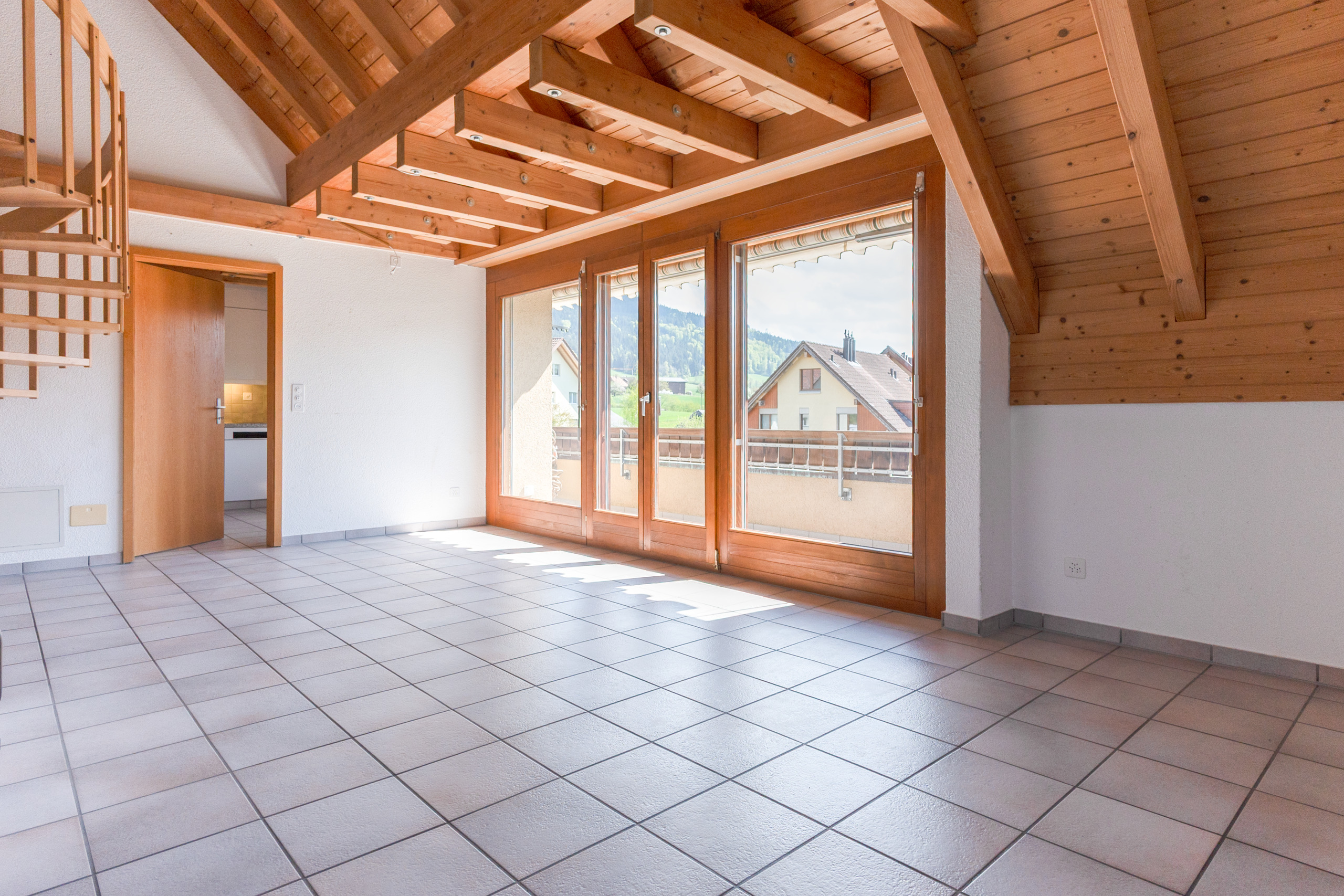Leerer Dachgeschossraum mit Balkonblick