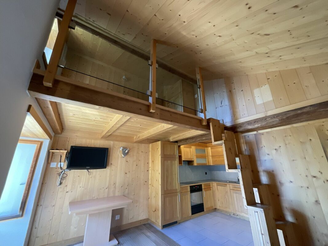 Holzverkleideter Wohnraum mit offener Küche und Galerie