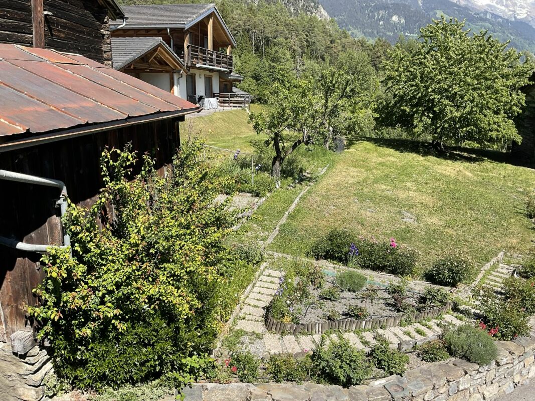 Alpiner Garten mit Holzhaus und Berghang