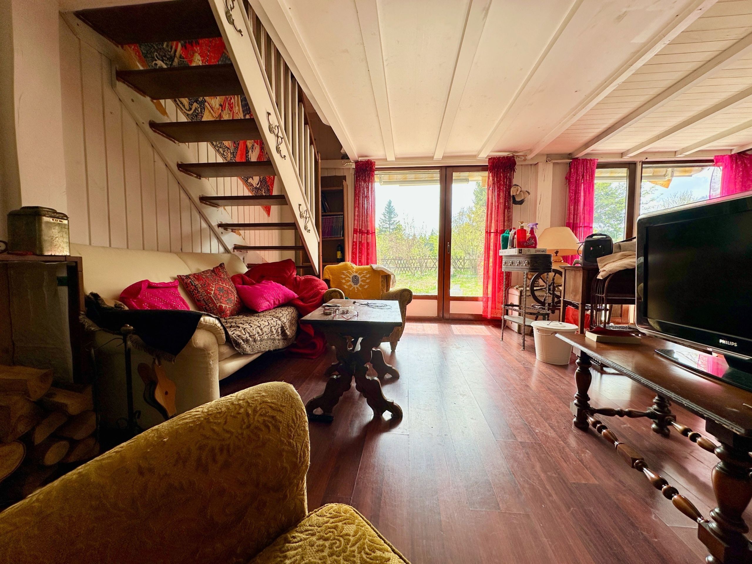Gemütliches Wohnzimmer mit Holztreppe und großen Fenstern