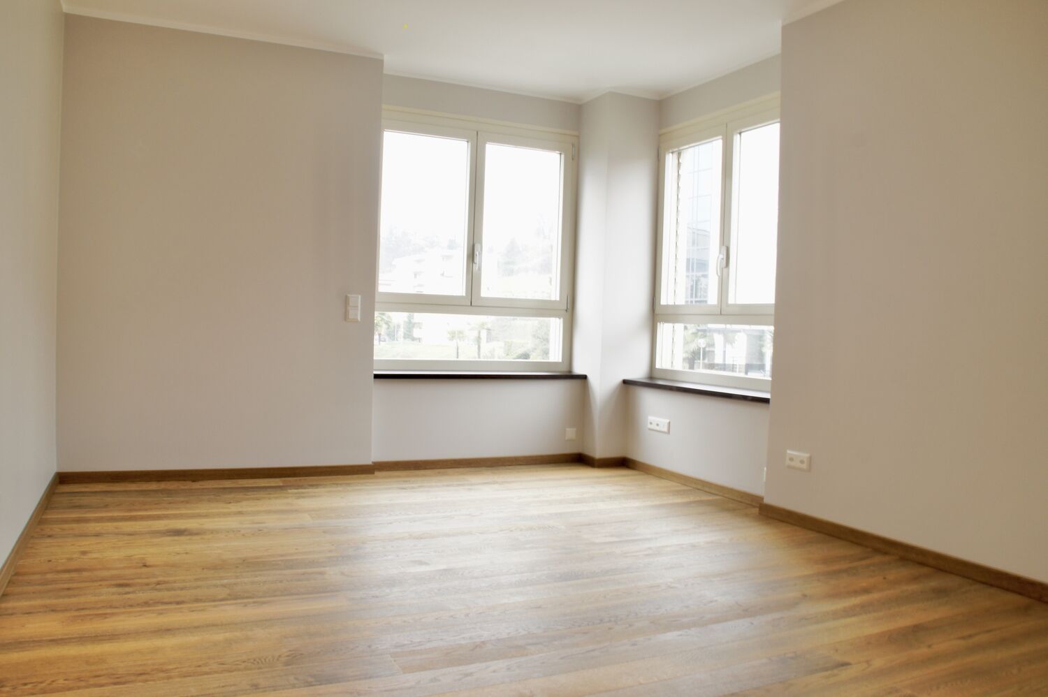 Helles, leer stehendes Zimmer mit großen Fenstern