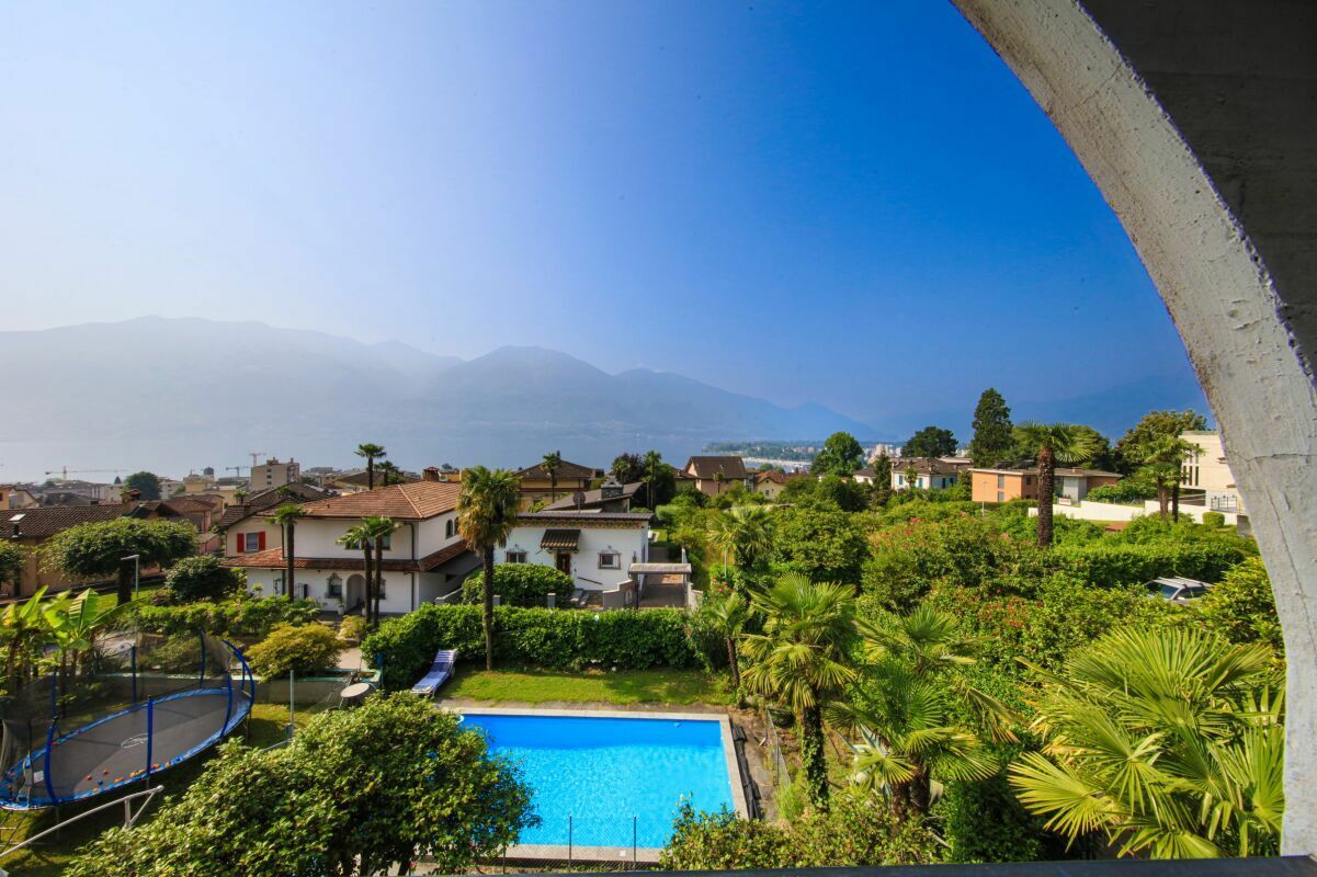 Blick über Garten und Pool auf Wohnhäuser und Berge