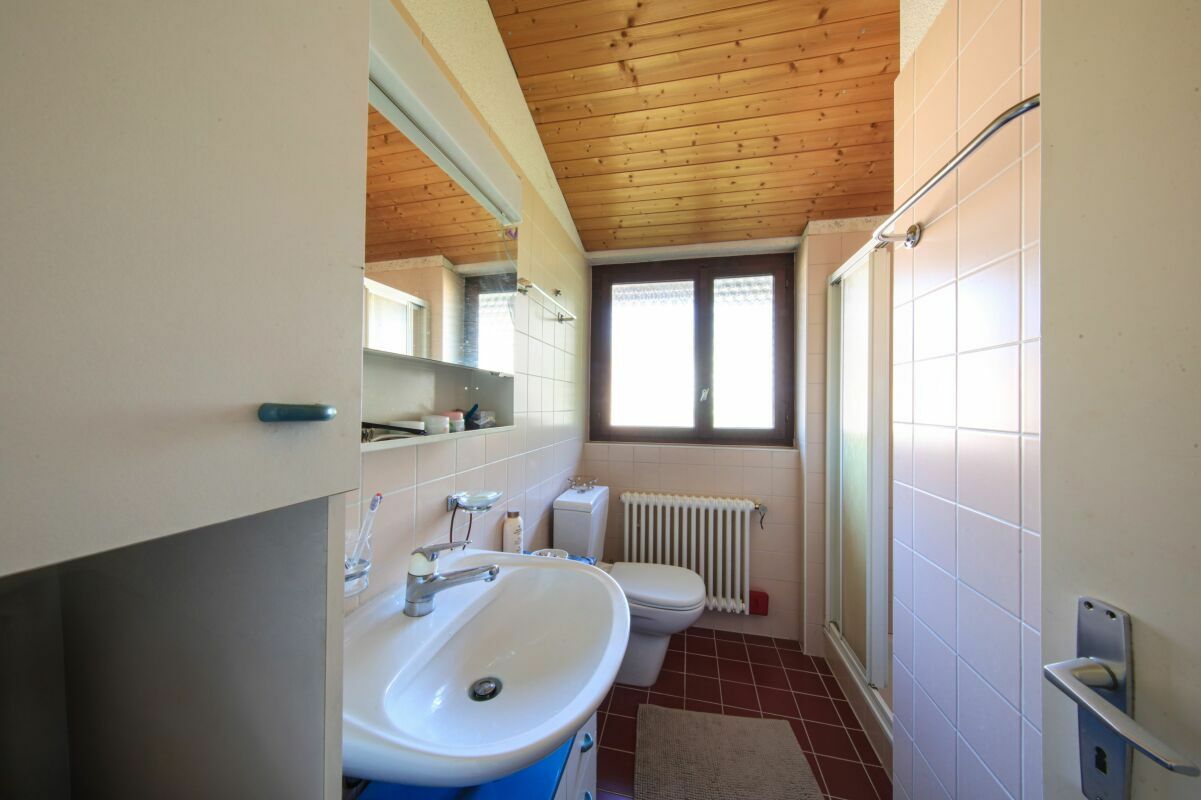 Kleines Badezimmer mit Dusche, Fenster und Holzdecke