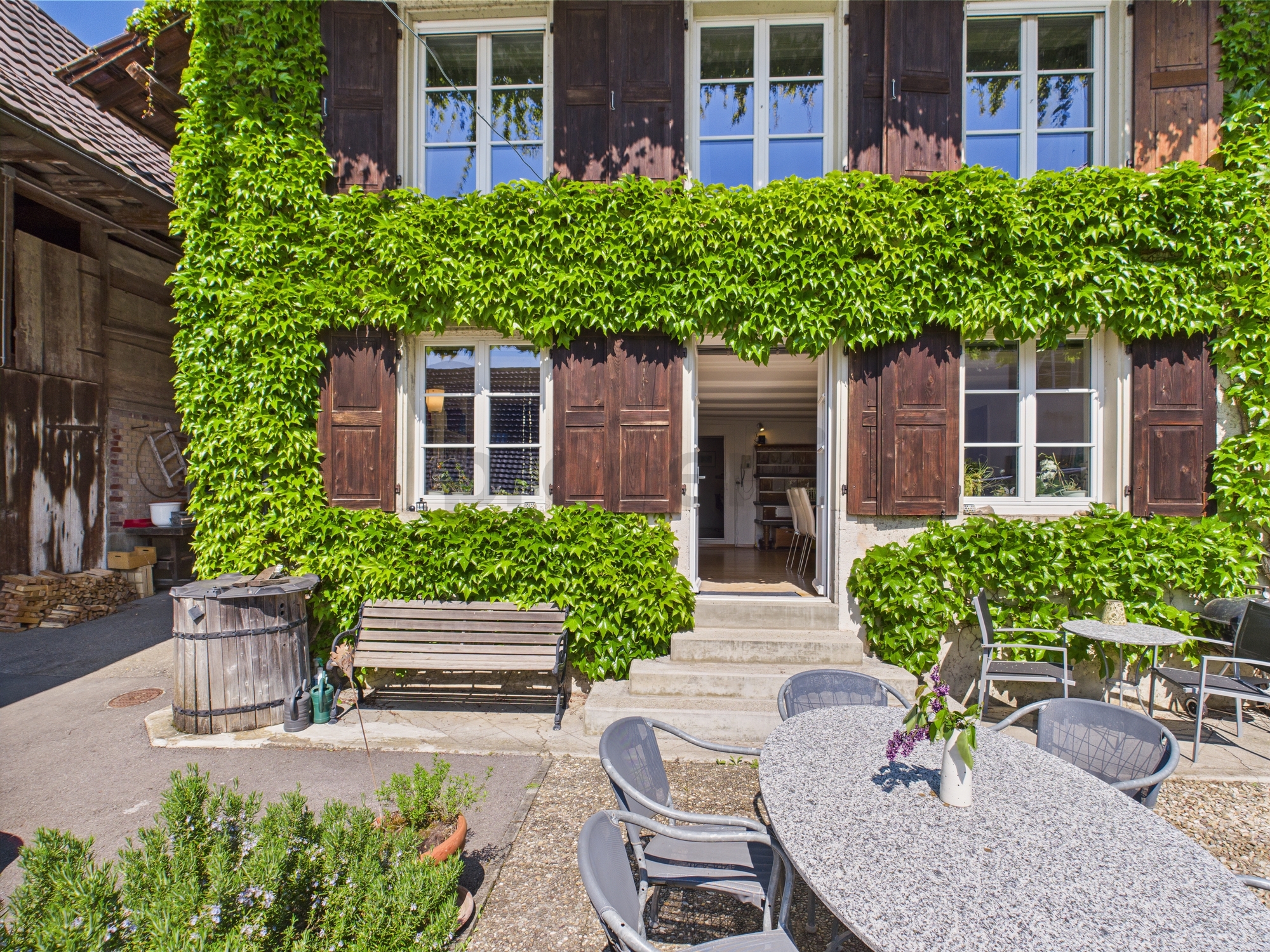 Mit Efeu bewachsene Hausfassade mit Sitzplatz
