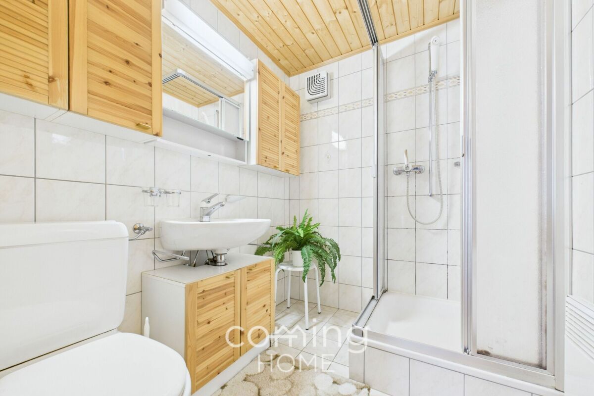 Helles Badezimmer mit Dusche und Holzdetails