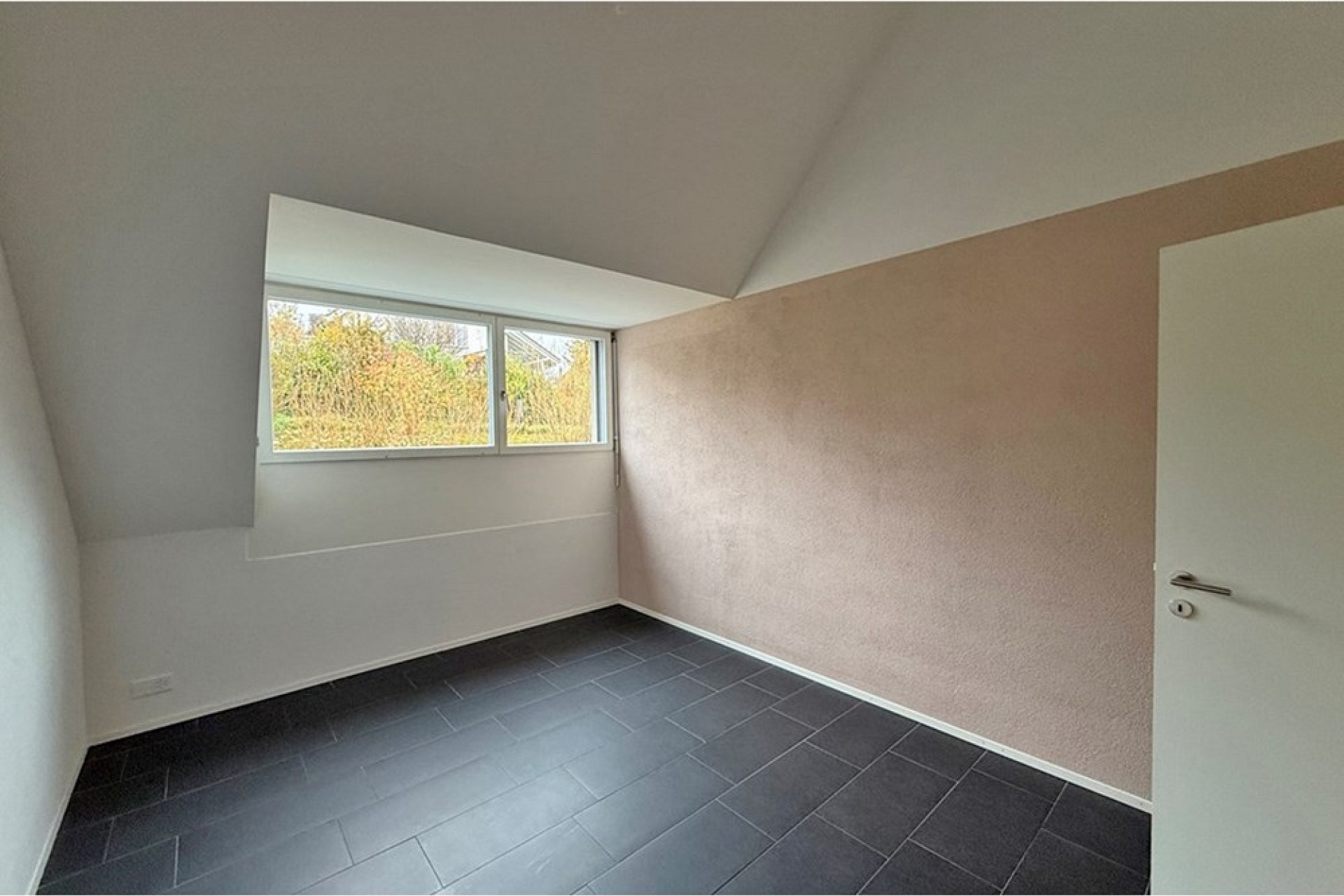 Leeres Zimmer mit Dachschräge und Fenster