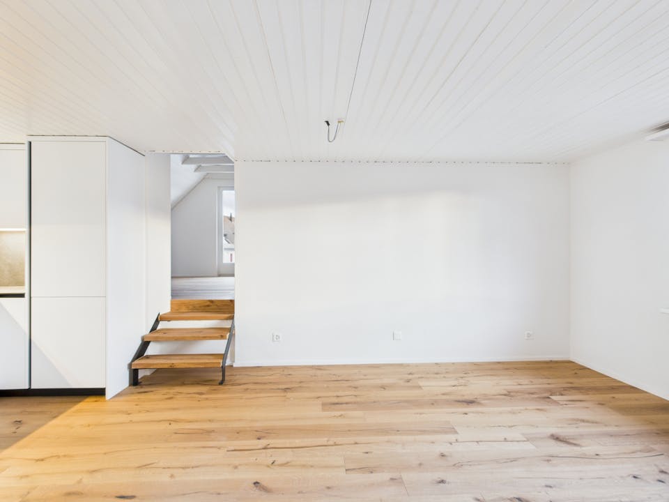 Heller leerer Innenraum mit Holzfußboden und kleiner Treppe