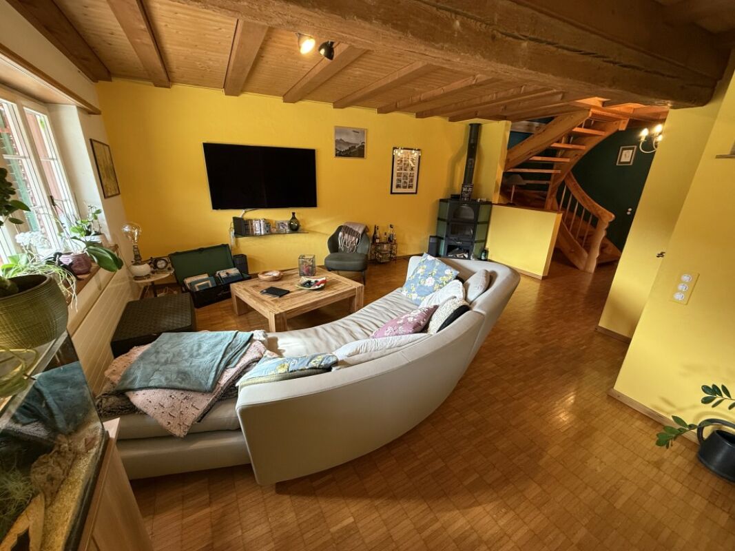 Gemütliches Wohnzimmer mit Holzdecke und Wendeltreppe