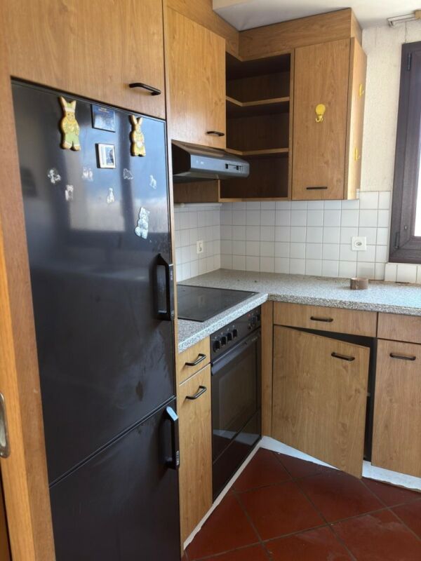 Kleine Küche mit Holzfronten und dunklem Kühlschrank