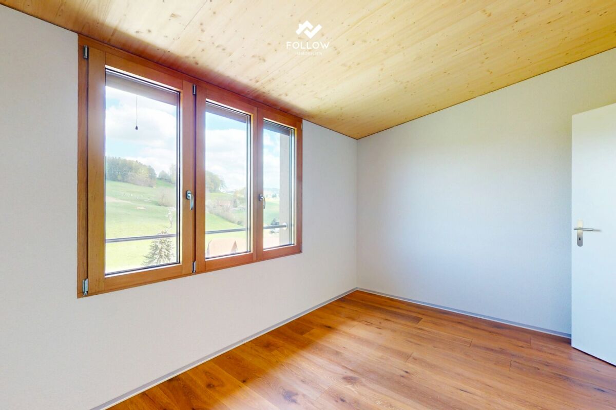 Heller, leerer Raum mit Holzfenstern und Naturholzdecke