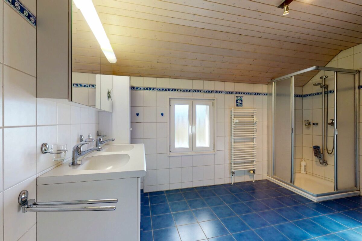Badezimmer mit blauem Fliesenboden und Holzdecke