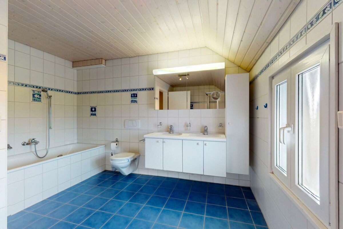 Badezimmer mit Badewanne, Doppelwaschbecken und blauem Fliesenboden