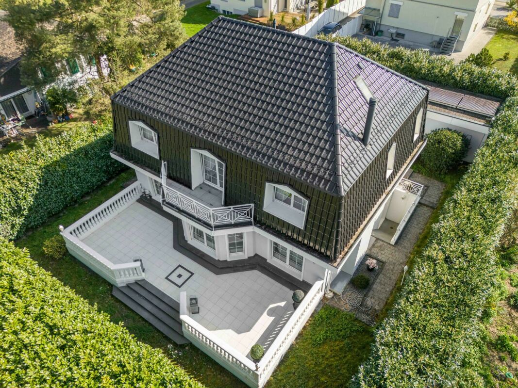 Drohnenaufnahme eines freistehenden Hauses mit großem Dach und Terrasse