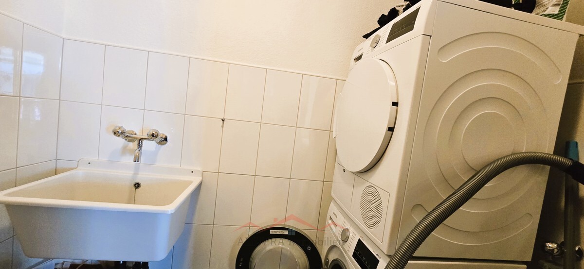Hauswirtschaftsraum mit Waschmaschine und Waschbecken