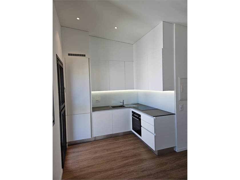 Moderne, weiße Einbauküche mit Holzoptikboden