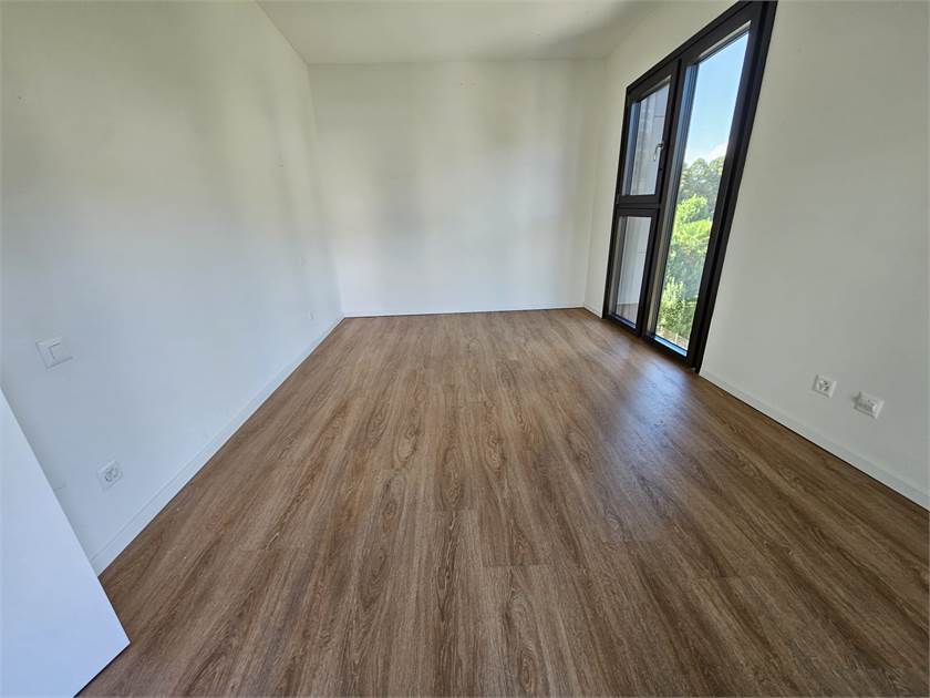 Leerer heller Raum mit Holzboden und großem Fenster