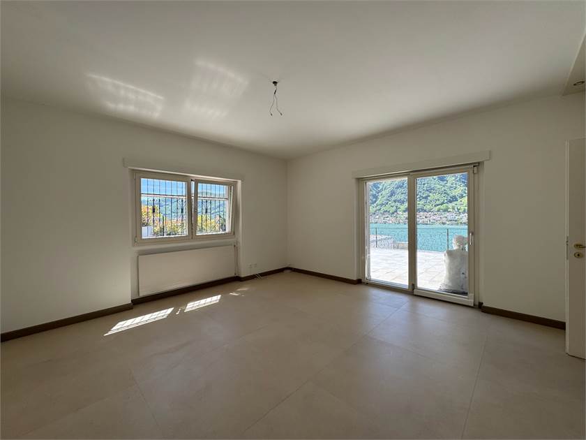 Leerer Wohnraum mit Balkon- bzw. Terrassenzugang und Berg-/Wasserblick
