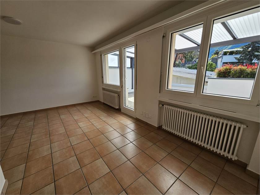 Leerer Innenraum mit Terrakottafliesen und großen Fenstern